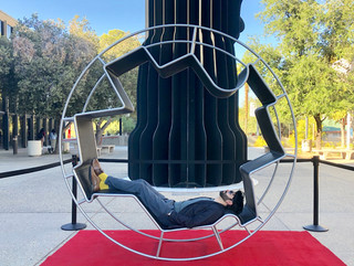 Image of a man lying in a wheel-like workspace outdoors on a red carpet