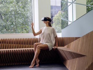 Image of a woman wearing a VR headset sitting on a wooden bench