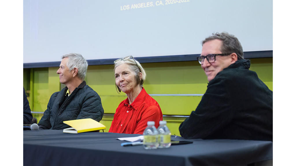 A photograph of three people sitting at a table and looking into the audience