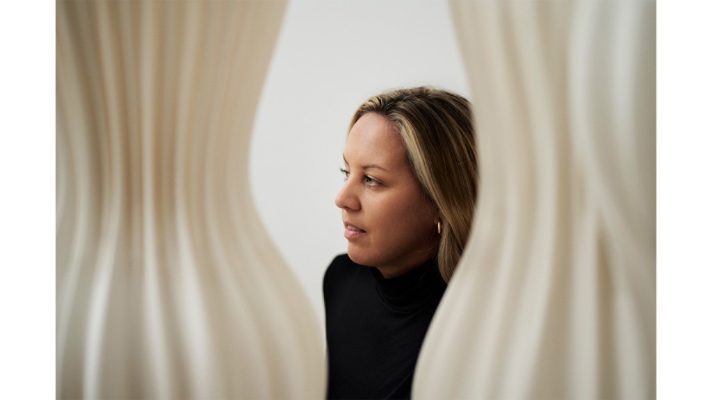 A photograph of a woman with a black sweater, between two tan-colored cylindrical shapes