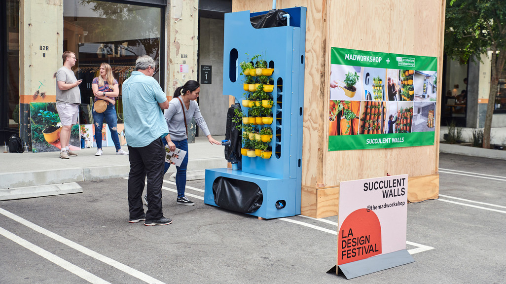 A student pointing to various elements of a rainwater harvesting system attached to a temporary wooden structure