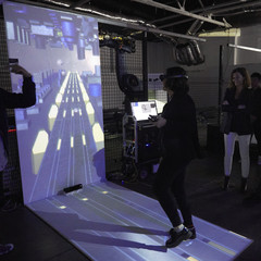 Image of a woman experiencing a VR environment surrounded by a group of people